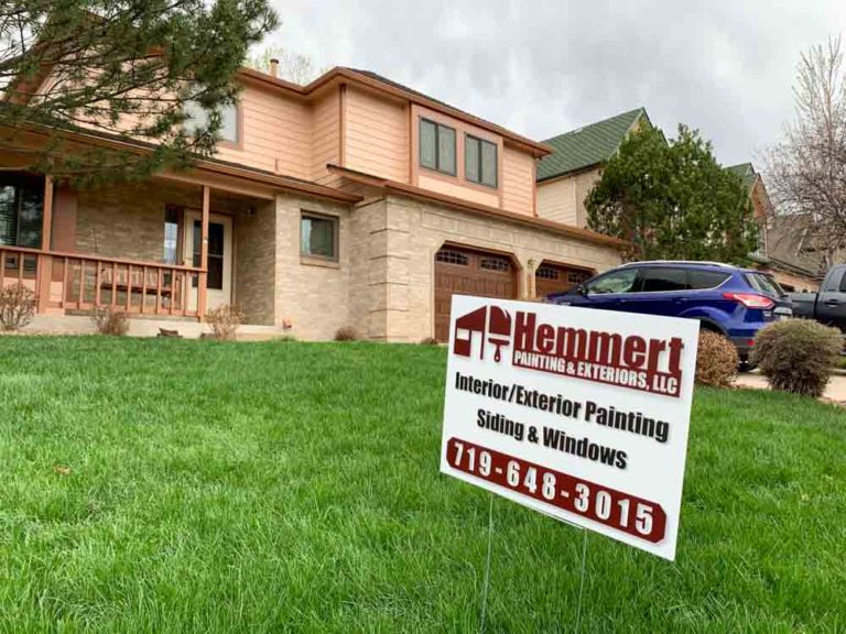 Hemmert Painting & Exteriors signage with a contact number and a house painting project
