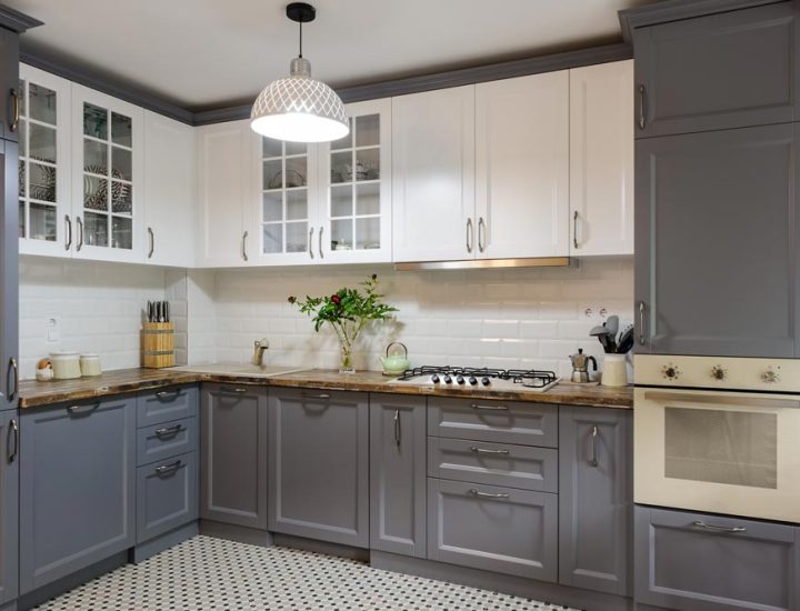 a beautiful kitchen with white and gray cabinets and a hanging light at the center