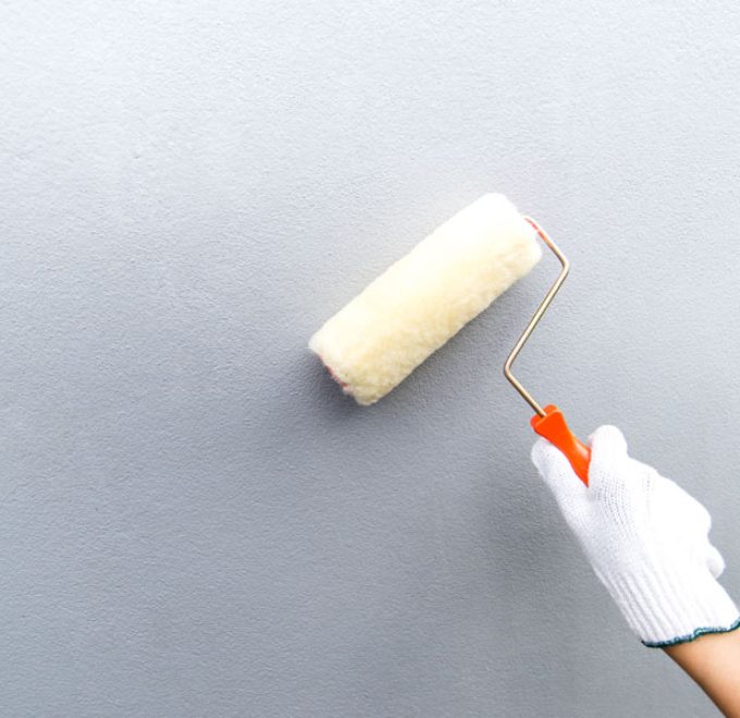 close up of a hand of a painter wearing a white glove holding a paint roller brush ready to paint the wall