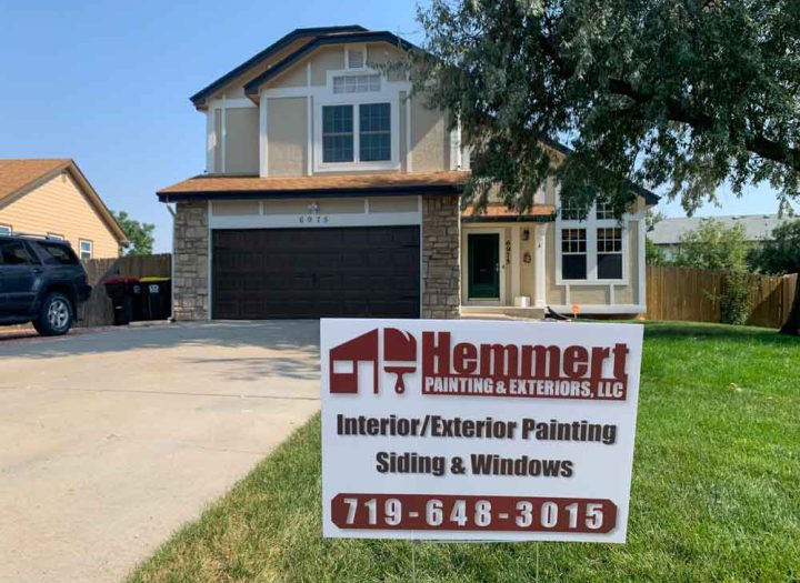 Hemmert Painting & Exteriors signage with a contact number and a house painting project
