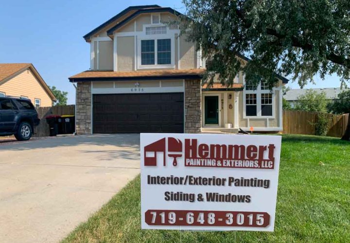 Hemmert Painting & Exteriors signage with a contact number and a house painting project