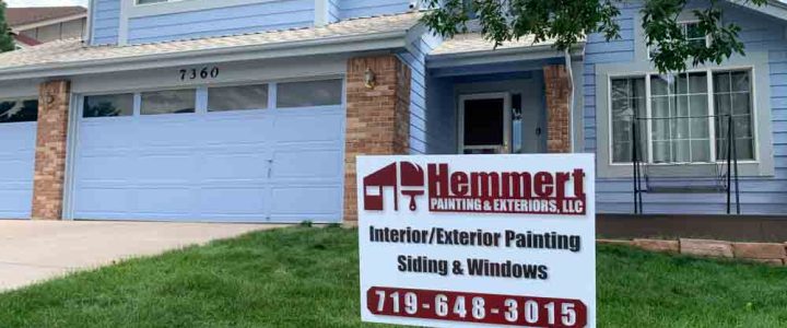 Hemmert Painting & Exteriors signage with a contact number and a house painting project