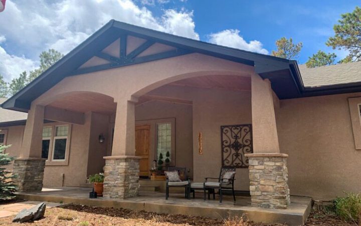 Bungalow home with light-colored walls and dark-colored rooftop.