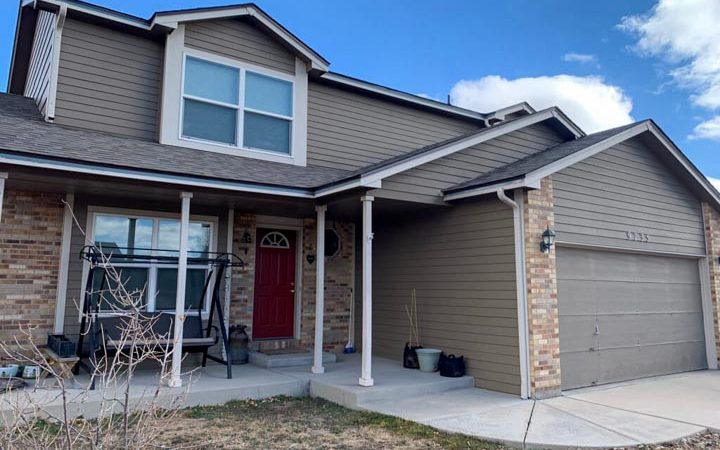 newly painted siding, window trim, posts and door of a beautiful house with a sidewalk going to the garage