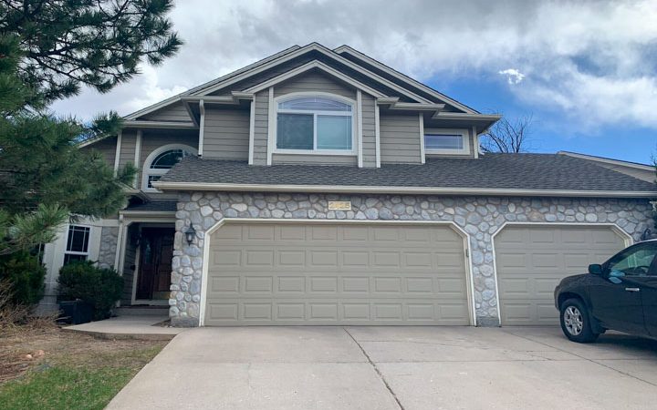 a beautiful house with a newly painted garage doors and a concrete driveway